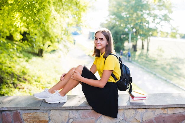 Jolie adolescente assise sur une clôture