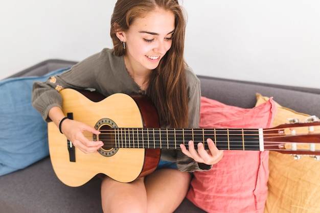 Jolie adolescente jouant de la guitare à la maison