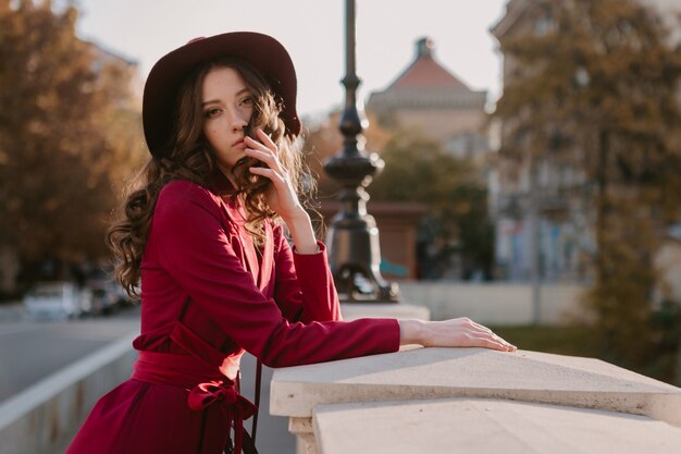 Jolie belle femme élégante en costume violet marchant dans la rue de la ville, tendance de la mode printemps été automne saison portant chapeau, tenant sac à main