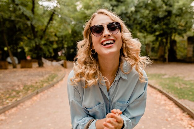 Jolie blonde souriante femme candide marchant dans le parc en tenue d'été