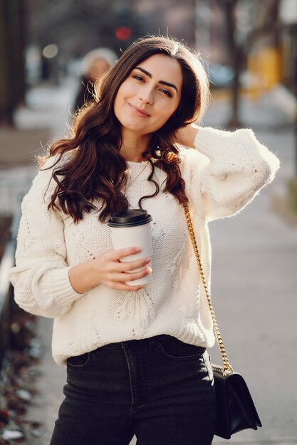 Jolie brune dans un pull blanc dans une ville