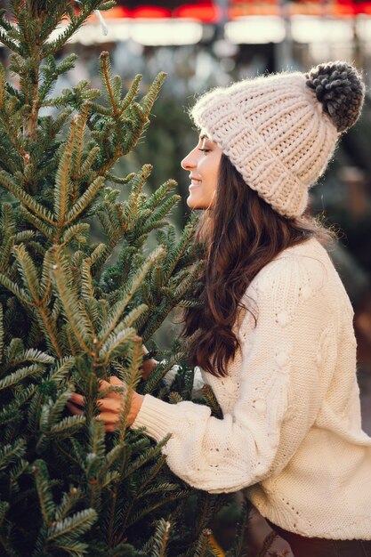 Jolie brune dans un pull blanc avec sapin de Noël