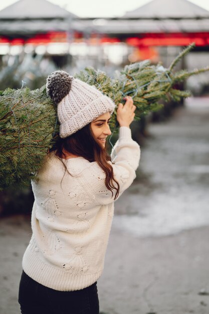 Jolie brune dans un pull blanc avec sapin de Noël