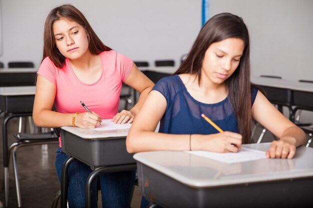 Jolie brune essayant de tricher lors d'un test au lycée