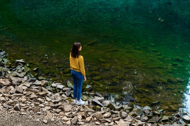 Jolie brunette femme appréciant le paysage des montagnes, debout près du lac