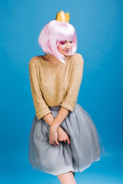 Photo gratuite jolie charmante jeune femme en jupe de tulle gris, avec coupe de cheveux rose. pull doré, couronne sur la tête, exprimant des émotions timides, souriant les yeux fermés, fête, fête.