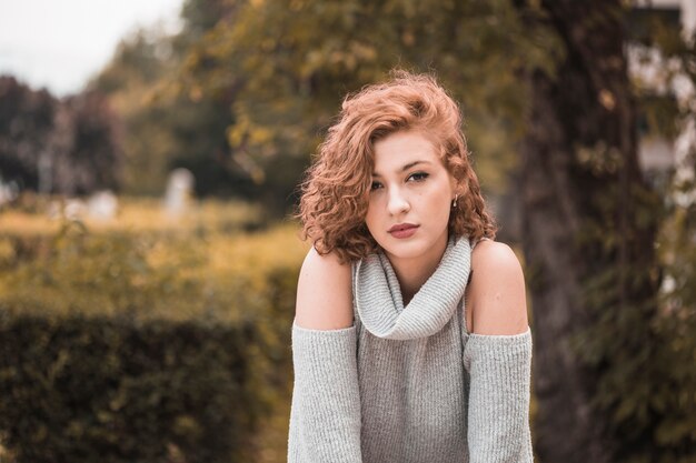 Jolie dame aux cheveux bouclés courts dans le jardin public