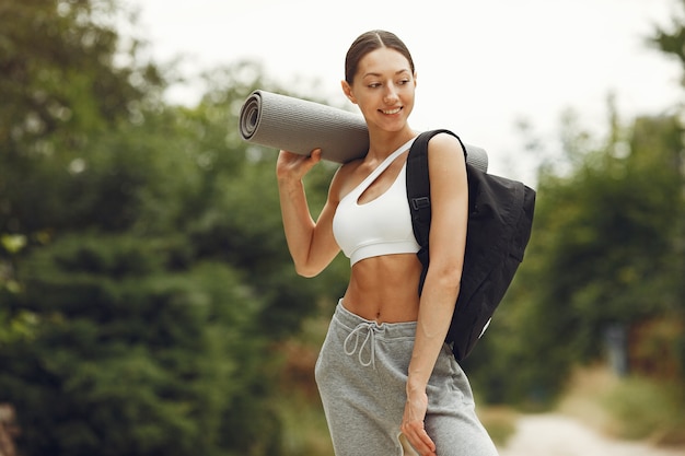 Jolie dame dans un parc. Brunette se prépare au yoga. Fille en tenue de sport.