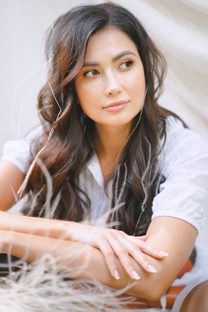 Photo gratuite jolie dame en longue robe blanche assise sur l'herbe et pensant pendant la journée.