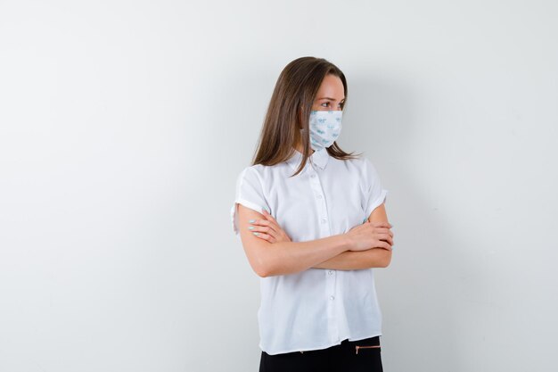 Jolie dame en t-shirt portant un masque et tenant les bras croisés