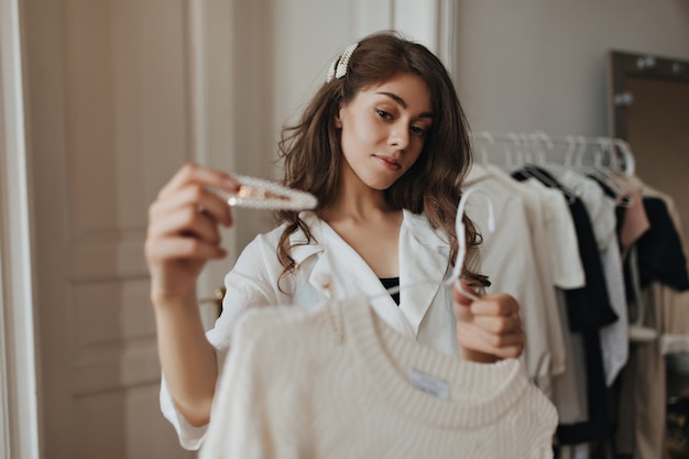 Jolie dame tenant une épingle à cheveux blanche et un pull beige