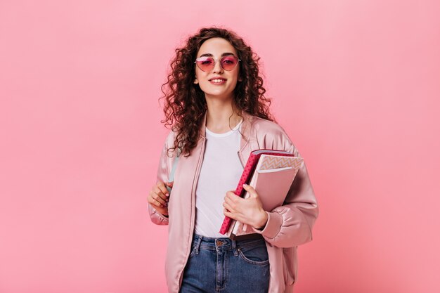Jolie dame en tenue rose et lunettes de soleil tenant un livre