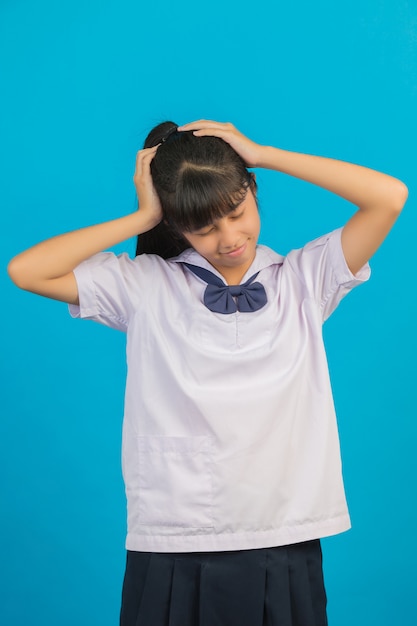 Jolie écolière asiatique faisant des maux de tête sur un bleu.
