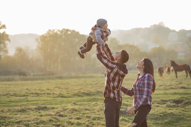 Jolie famille marchant dans un parc d'été au coucher du soleil