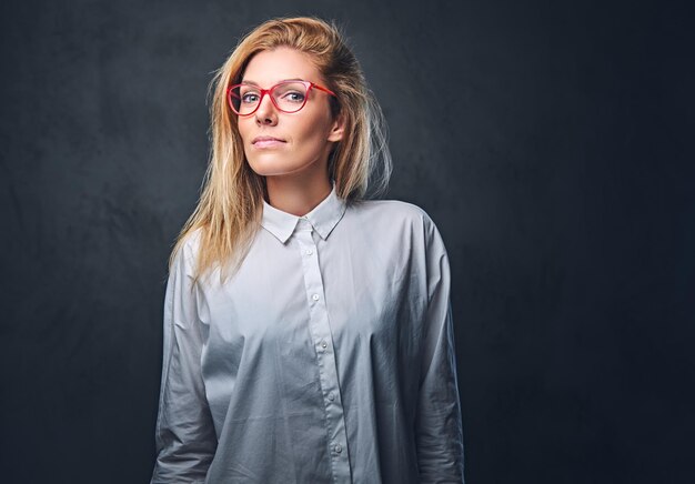 Jolie femme d'affaires blonde dans une chemise blanche sur fond gris.