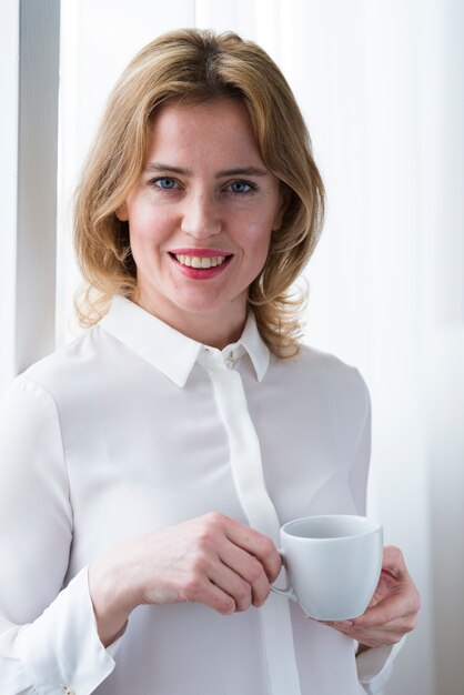 Jolie femme d&#39;affaires debout avec une tasse de café