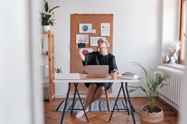 Une jolie femme d'affaires prend un selfie dans son bureau confortable