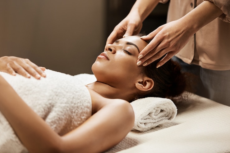 Photo gratuit jolie femme africaine bénéficiant d'un massage du visage dans le salon spa.