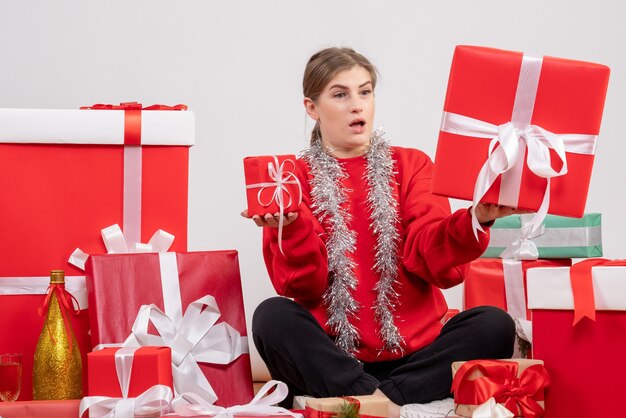 Jolie femme assise autour de cadeaux de Noël sur blanc