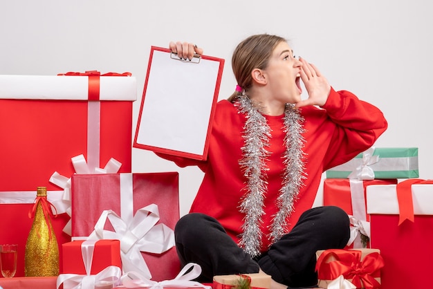 Jolie femme assise autour des cadeaux de Noël avec note sur blanc