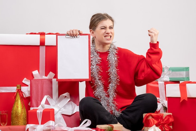 Jolie femme assise autour des cadeaux de Noël avec note sur blanc