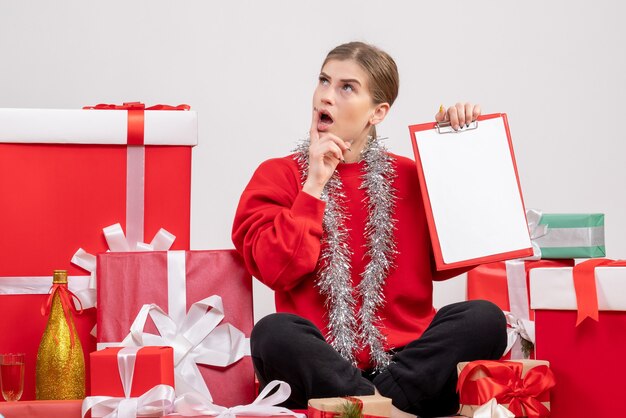 Jolie femme assise autour de cadeaux de Noël avec note pensée sur blanc