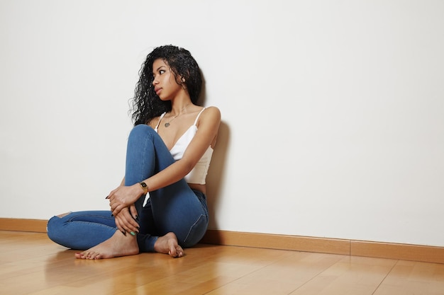 Jolie femme assise sur un plancher en bois dans une pièce lumineuse