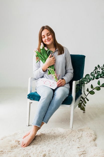 Jolie femme assise avec des tulipes et une carte de voeux