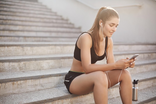 Jolie femme athlétique sportive s'asseoir sur les escaliers en plein air près de