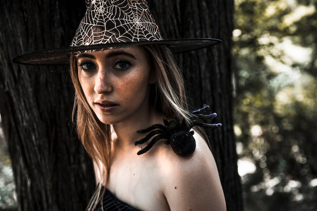 Jolie femme au chapeau et araignée artificielle sur l&#39;épaule