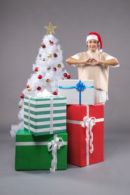 Jolie femme autour des cadeaux de Noël sur fond gris