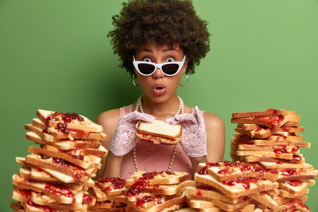 Jolie femme aux cheveux afro entourée de sandwiches en gelée de beurre de cacahuète