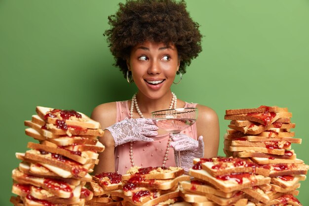 Jolie femme aux cheveux afro entourée de sandwiches en gelée de beurre de cacahuète