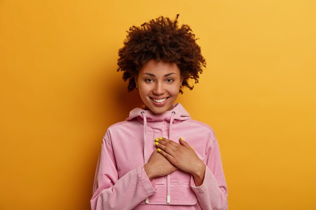 Jolie femme aux cheveux bouclés appuie sur les paumes du cœur