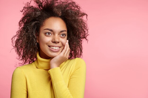 Jolie femme aux cheveux bouclés et col roulé jaune