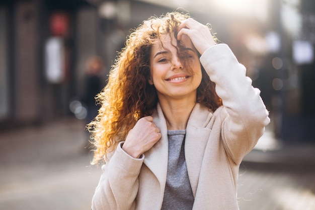 Jolie femme aux cheveux bouclés, marchant dans un manteau d'automne