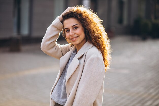 Jolie femme aux cheveux bouclés, marchant dans un manteau d'automne