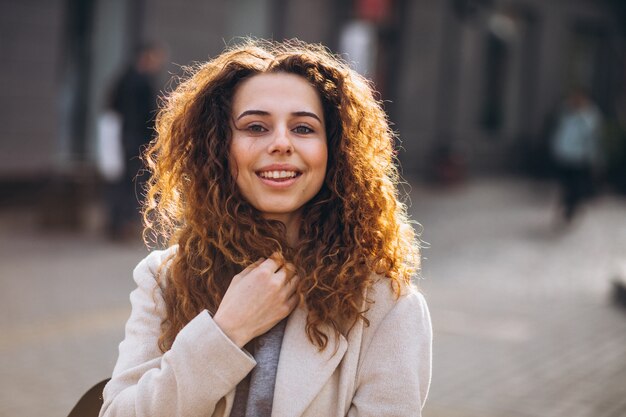 Jolie femme aux cheveux bouclés, marchant dans un manteau d'automne