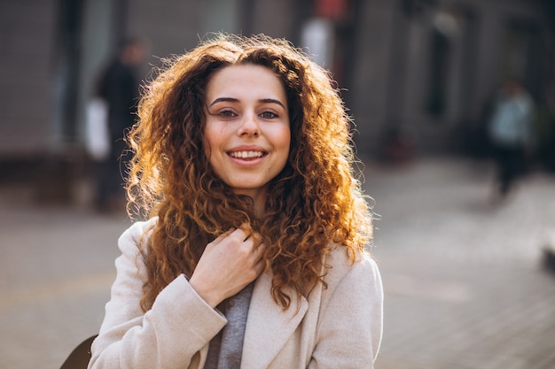 Jolie femme aux cheveux bouclés, marchant dans un manteau d'automne