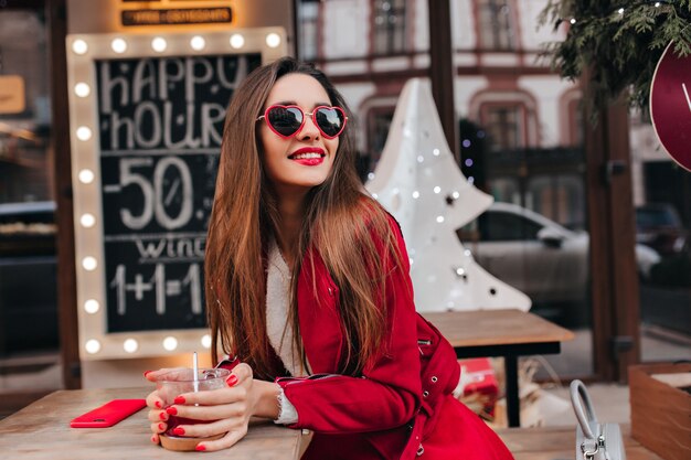 Jolie femme aux cheveux bruns brillants au café en week-end