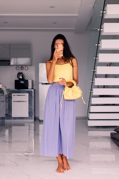 Jolie femme blogueuse de mode portant haut jaune et pantalon violet