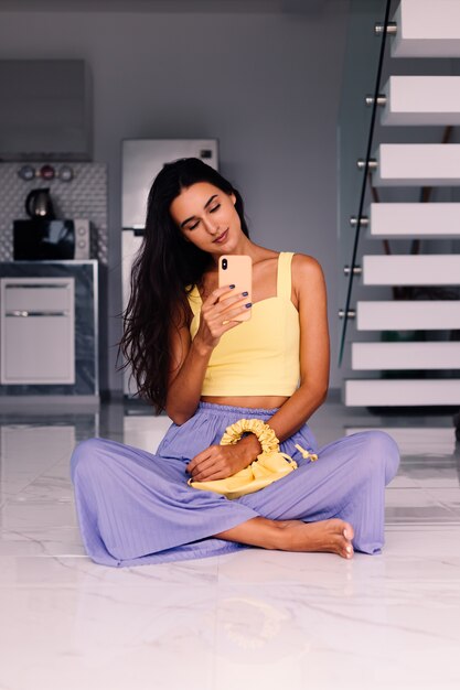 Jolie femme blogueuse de mode portant haut jaune et pantalon violet