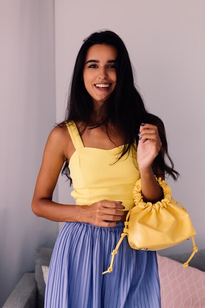 Jolie femme blogueuse de mode portant haut jaune et pantalon violet