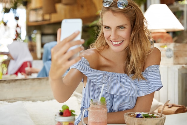 Jolie femme blonde assise dans un café