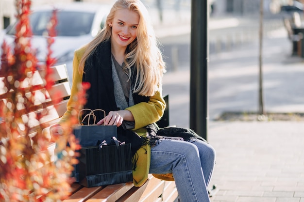 Jolie femme blonde séduisante heureuse avec des paquets dans la rue par temps chaud et ensoleillé