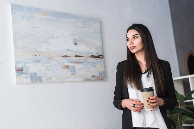 Jolie femme avec boisson au bureau