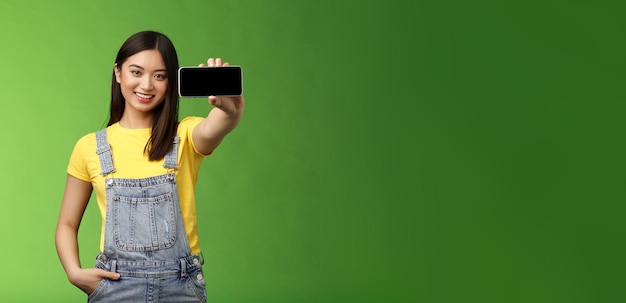 Photo gratuite jolie femme brune asiatique gaie introduire le jeu du smartphone tenir le spectacle horizontal du téléphone c