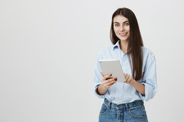 Jolie femme brune souriante à l'aide de tablette numérique