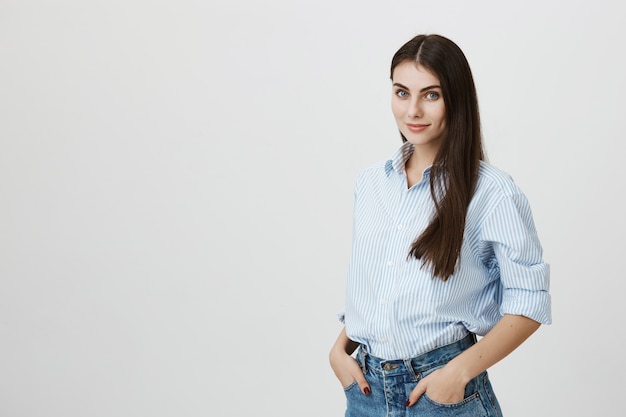 Jolie femme en chemise et jeans, main dans la main dans les poches