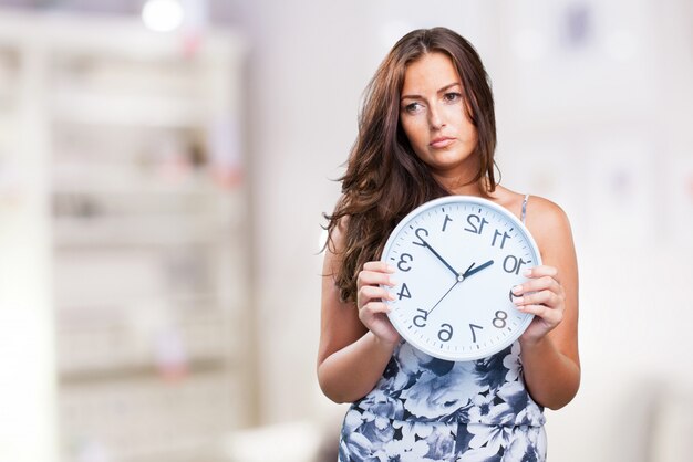 jolie femme en colère tenant une horloge